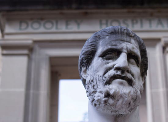 Hippocrates statue in front of Dooley Arch
